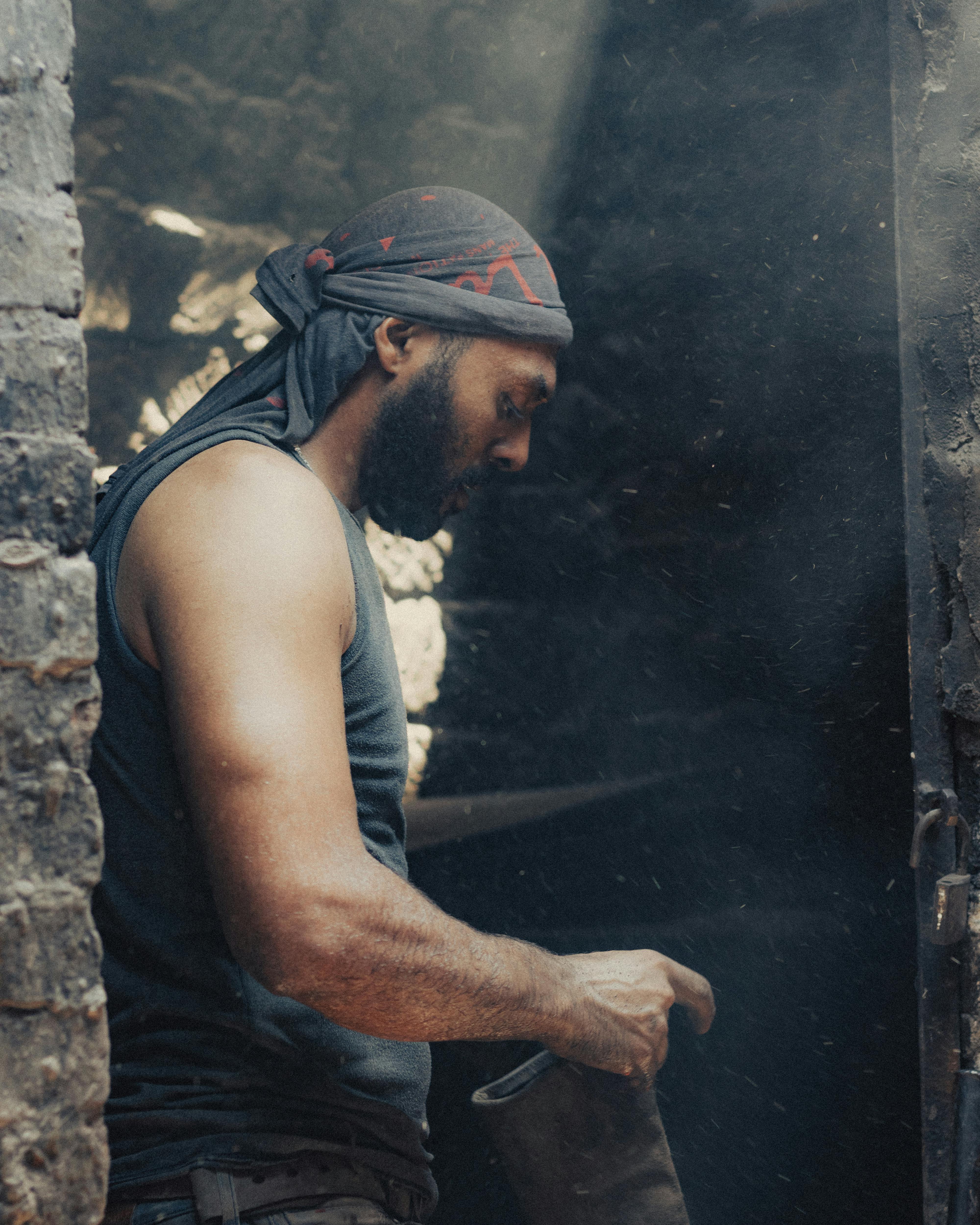 a man in a black shirt and bandana is standing in a doorway