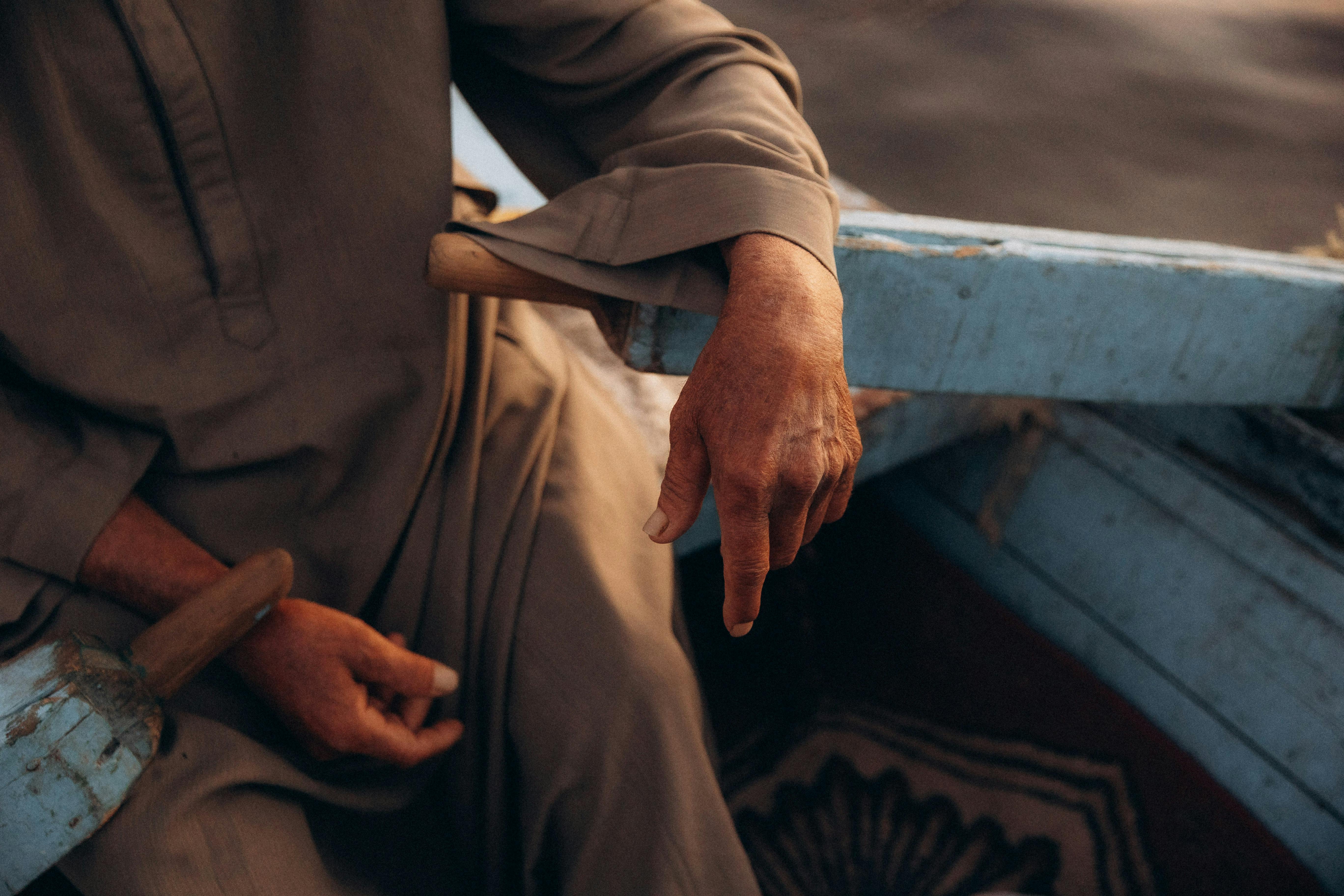 An elderly man's hand resting on a boat, showcasing tranquility on the Nile River.