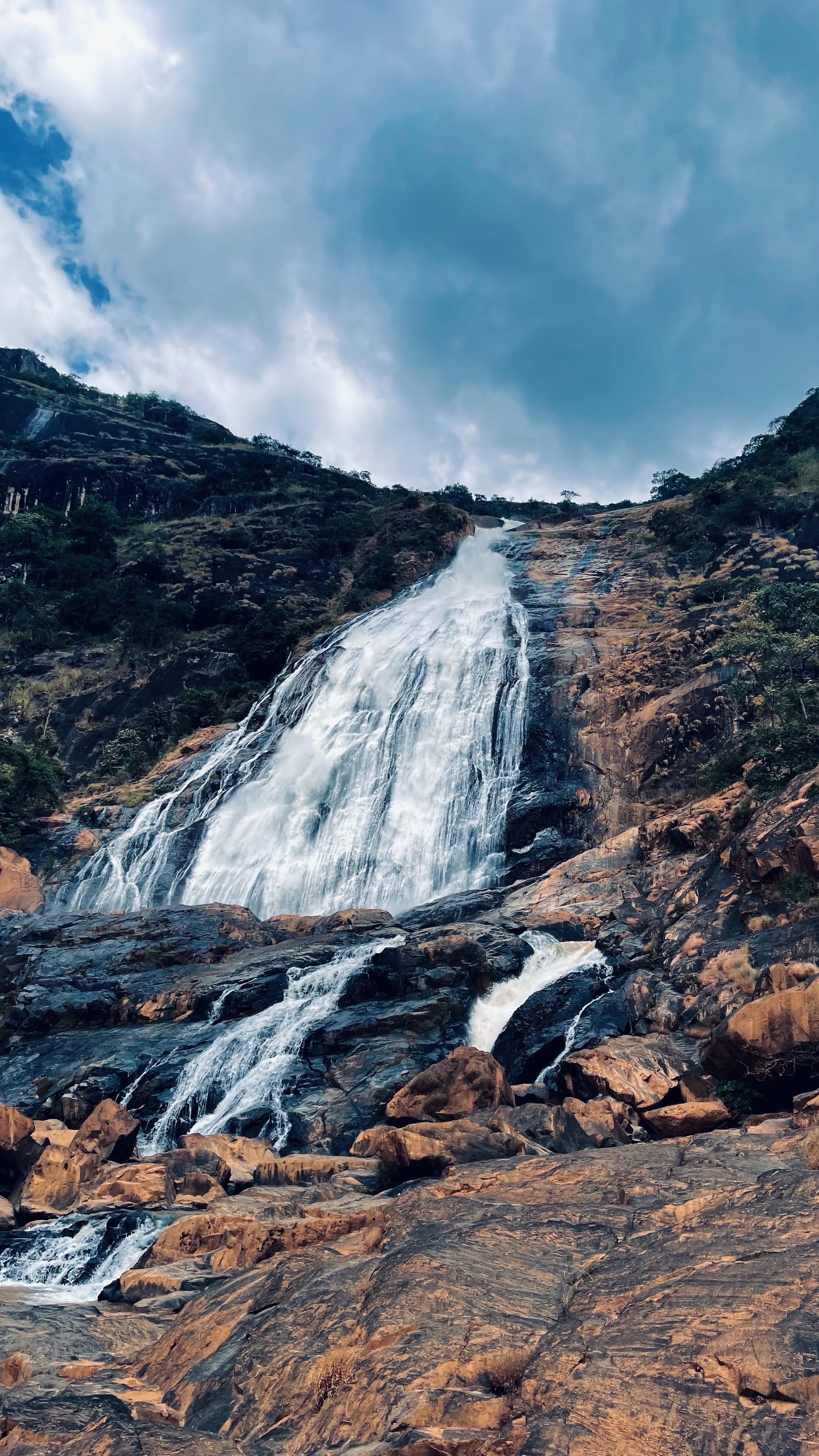 Stunning waterfall flows down rugged cliff amidst lush greenery, ideal for travel inspiration.