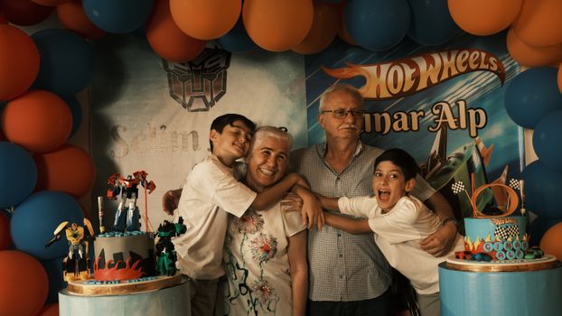 A joyful family celebrates a birthday with a themed party setup and cake.