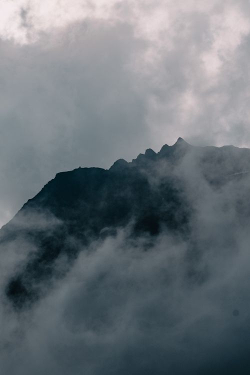 Free Cloud-covered mountain peak enveloped in mist, creating a dramatic and moody atmosphere. Stock Photo
