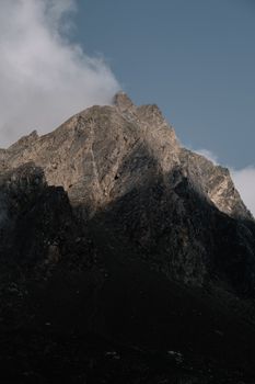 A rugged mountain peak under a clear blue sky, casting shadows in a winter landscape.