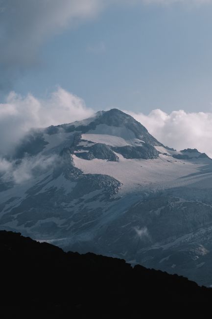 Breathtaking view of a snow-covered mountain peak surrounded by clouds.