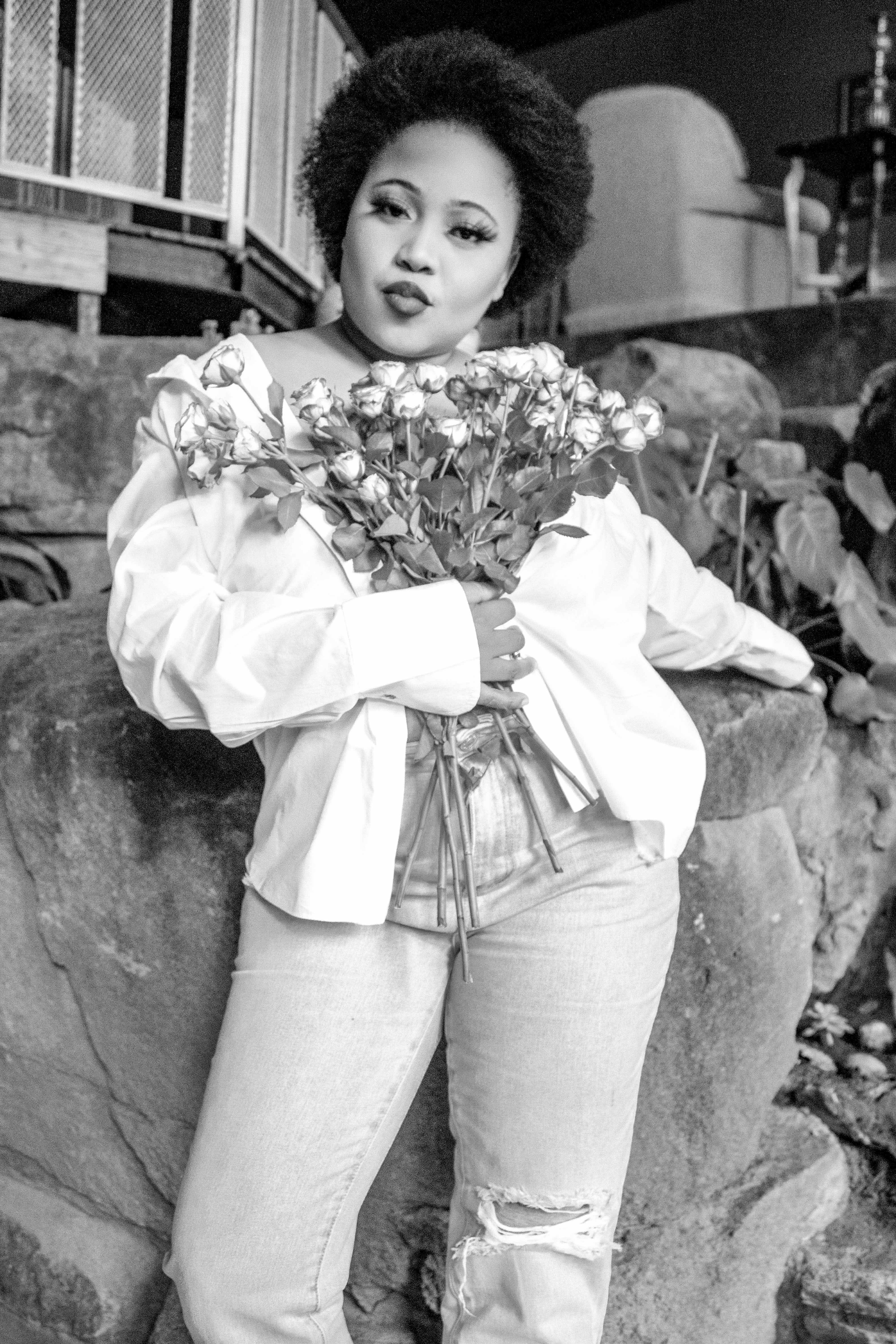Stylish woman with a bouquet poses in casual setting, adding a retro vibe.