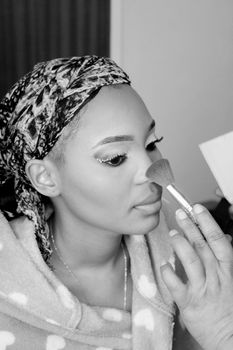 A close-up portrait of an adult woman applying makeup with a brush, emphasizing elegance and beauty.