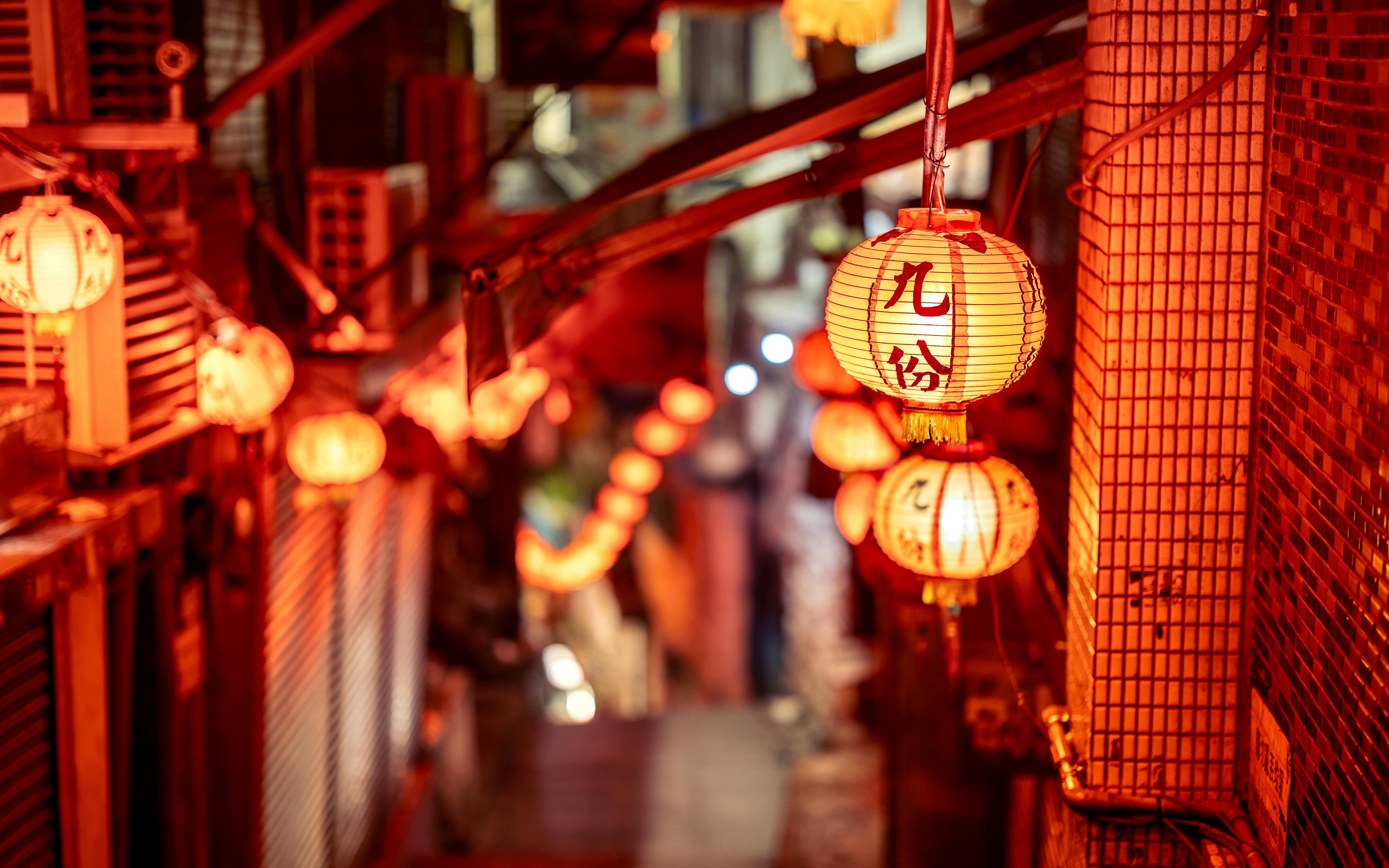 a narrow alley with red lanterns hanging from the ceiling