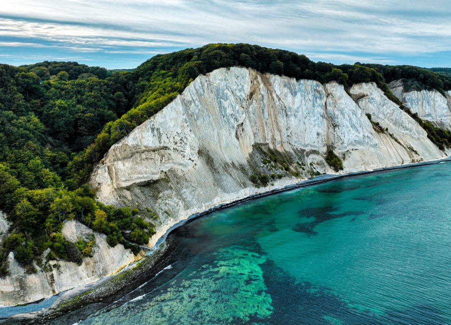 Stunning aerial view of white cliffs against a vibrant turquoise sea and lush greenery.