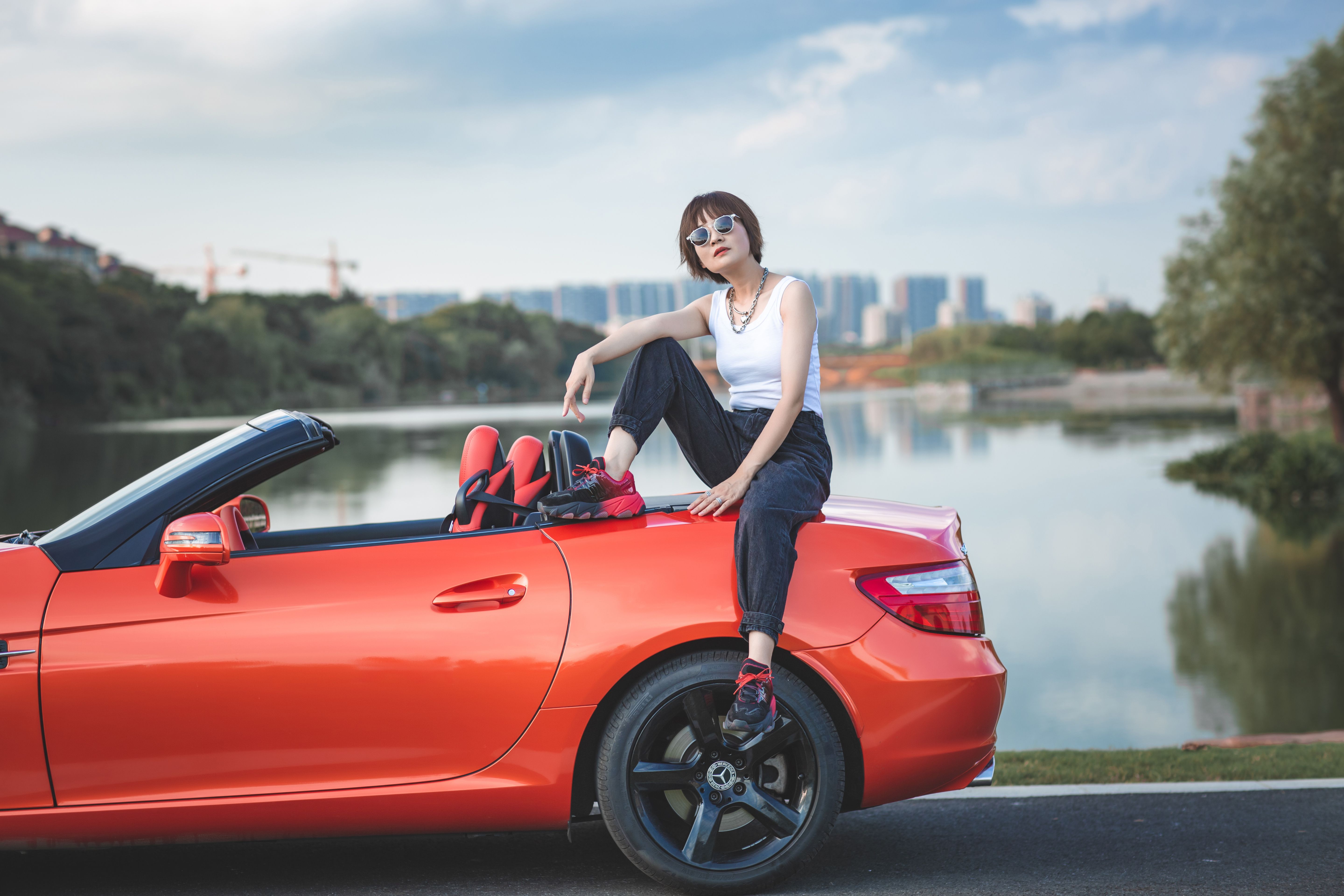 A woman sitting on top of a red sports car · Free Stock Photo