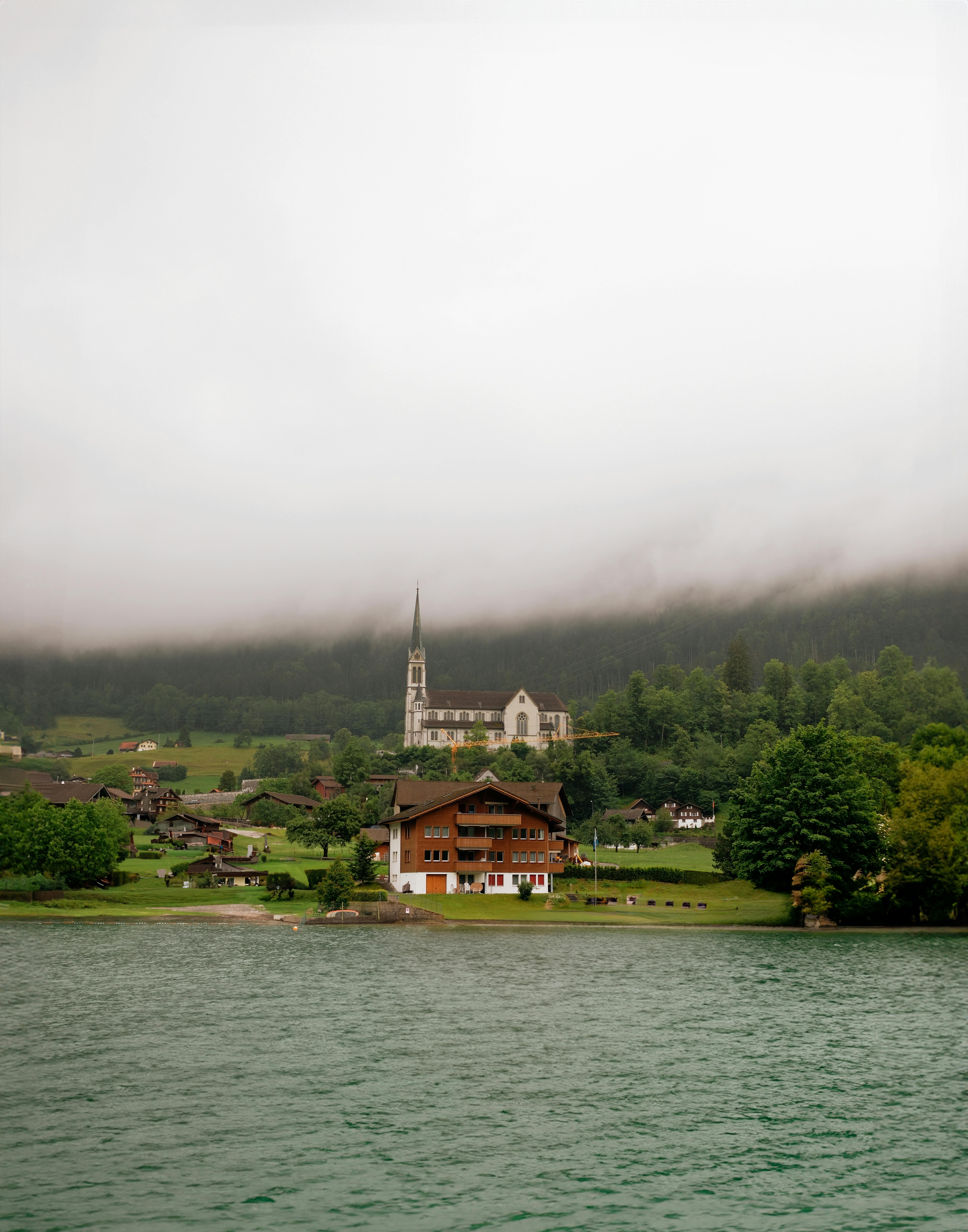 Peaceful landscape in Lungern, Switzerland with a church, lake, and misty hills.