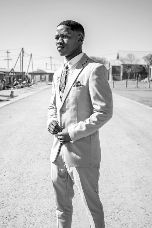Free Black and white portrait of a man in a suit standing outdoors on a sunny day. Stock Photo