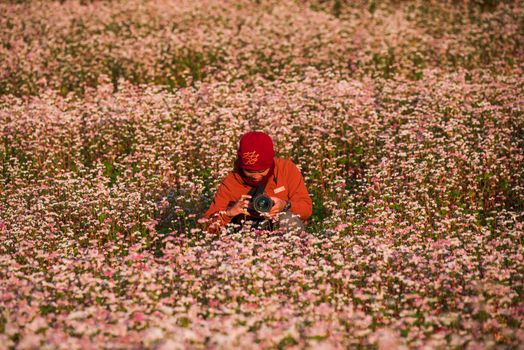 Photographer amidst a blooming field capturing nature's beauty with a camera.