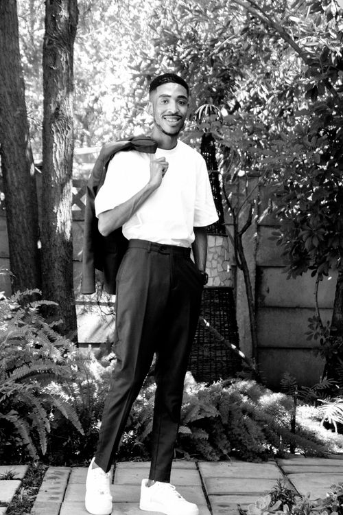 Free Black and white portrait of a trendy man in a garden, exuding confidence and style. Stock Photo