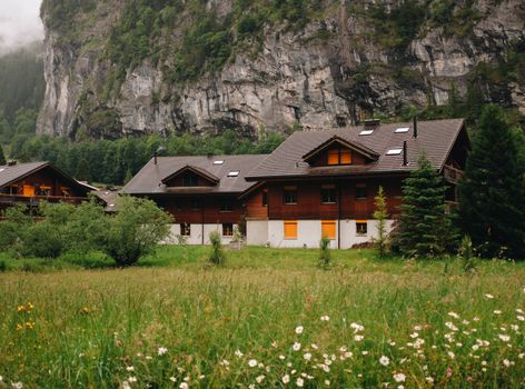 A picturesque alpine chalet nestled against a majestic mountain backdrop surrounded by lush greenery.