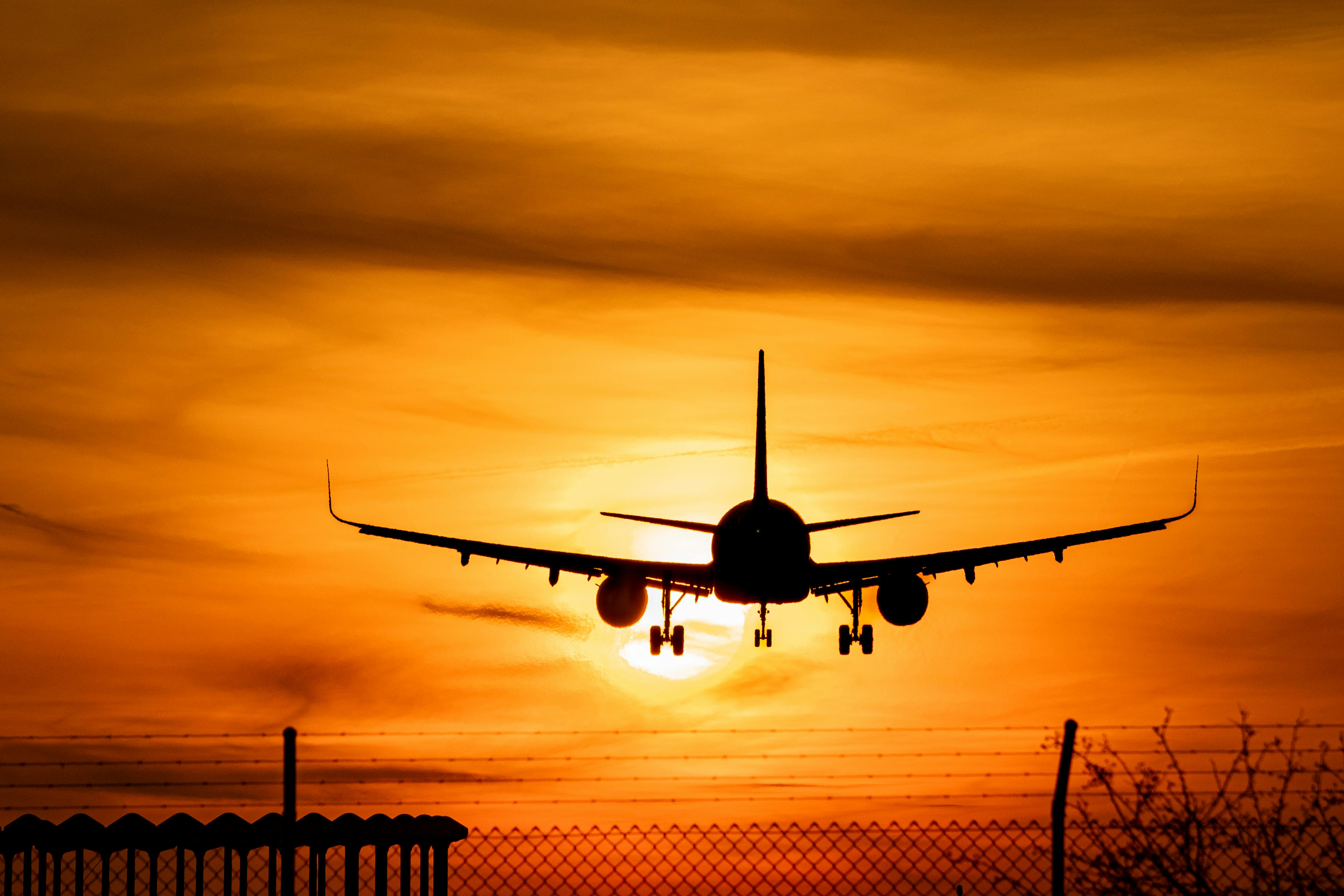 Free A silhouetted airplane descends against a vibrant sunset sky, symbolizing travel and adventure. Stock Photo