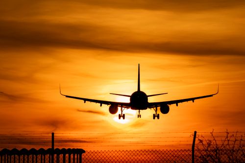 Free A silhouetted airplane descends against a vibrant sunset sky, symbolizing travel and adventure. Stock Photo