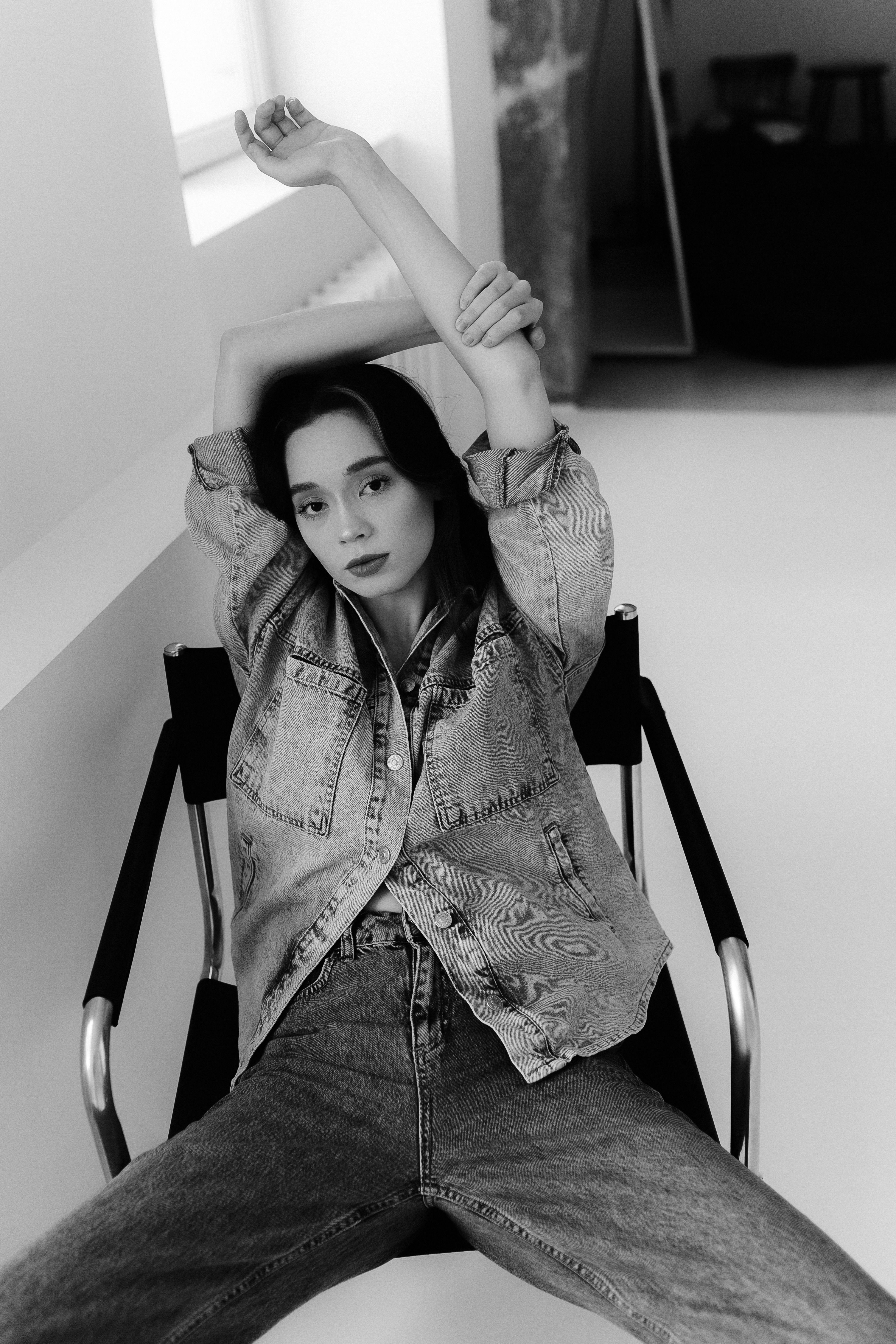 A woman in jeans and a denim jacket sitting on a chair · Free Stock Photo