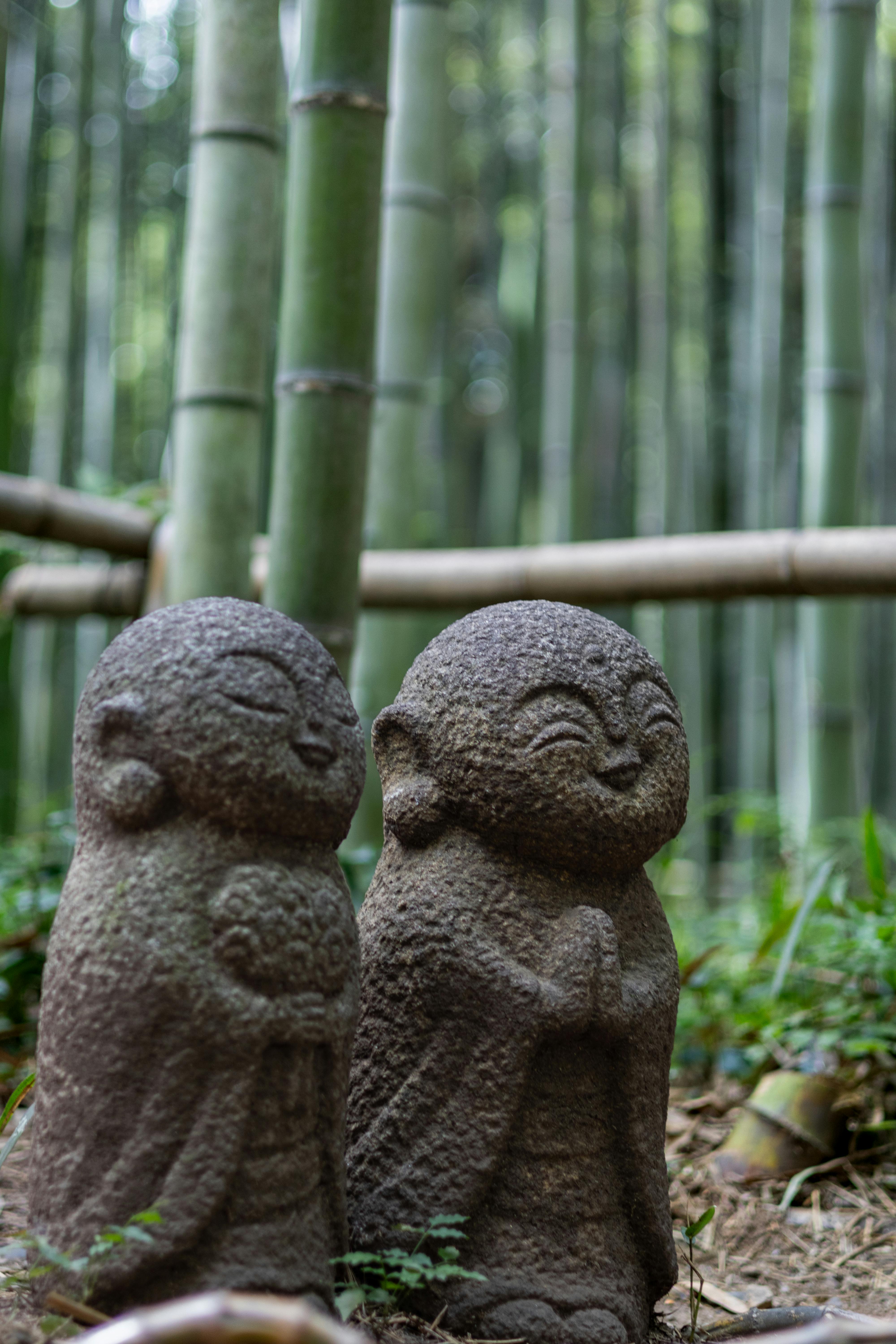 two stone statues in front of bamboo trees