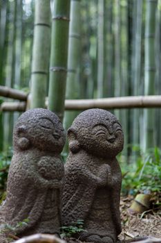 Serene stone statues amongst lush bamboo, capturing Zen tranquility in nature.