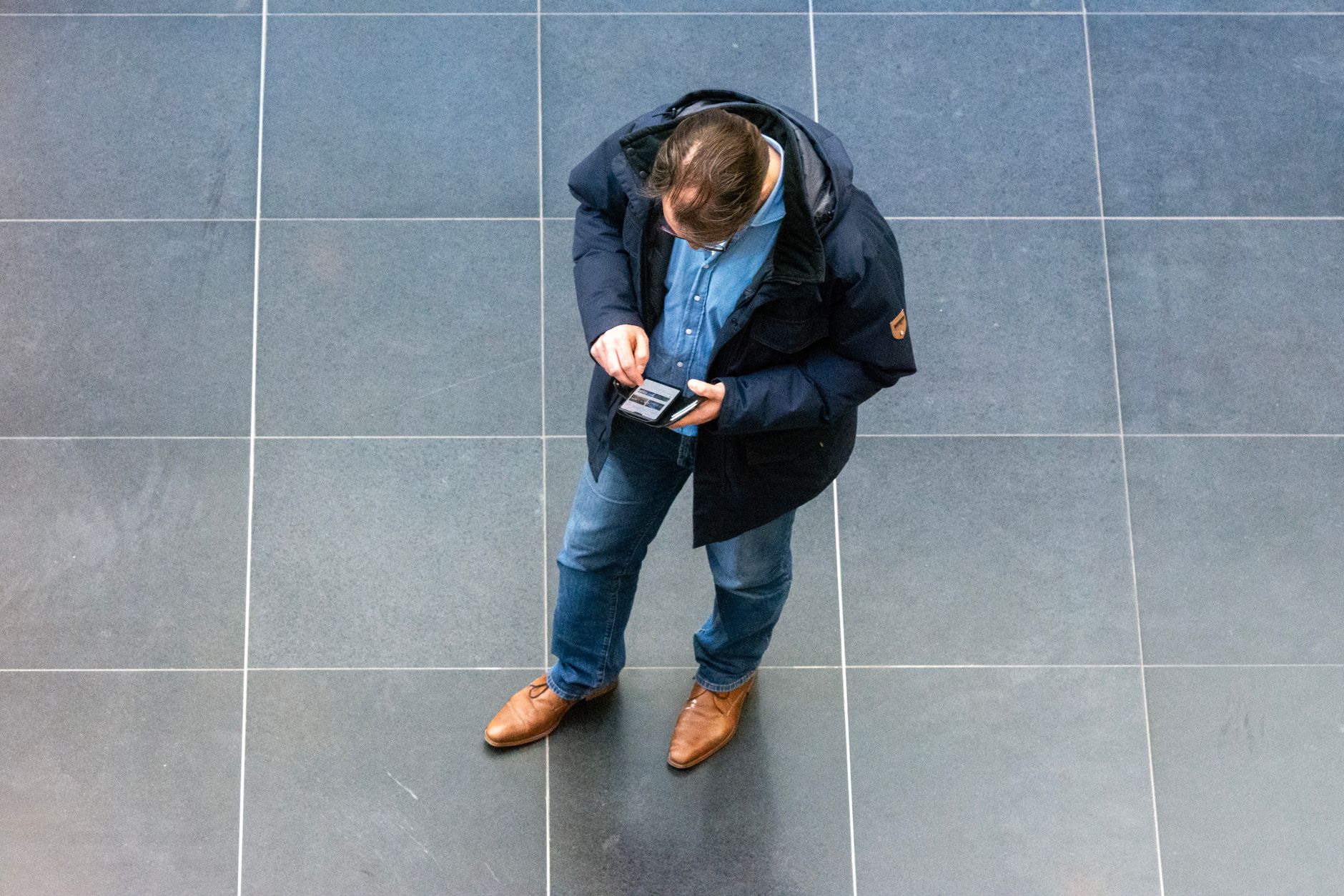 A supporter checking a mobile World Cup ticket beside a passport at a busy international airport terminal