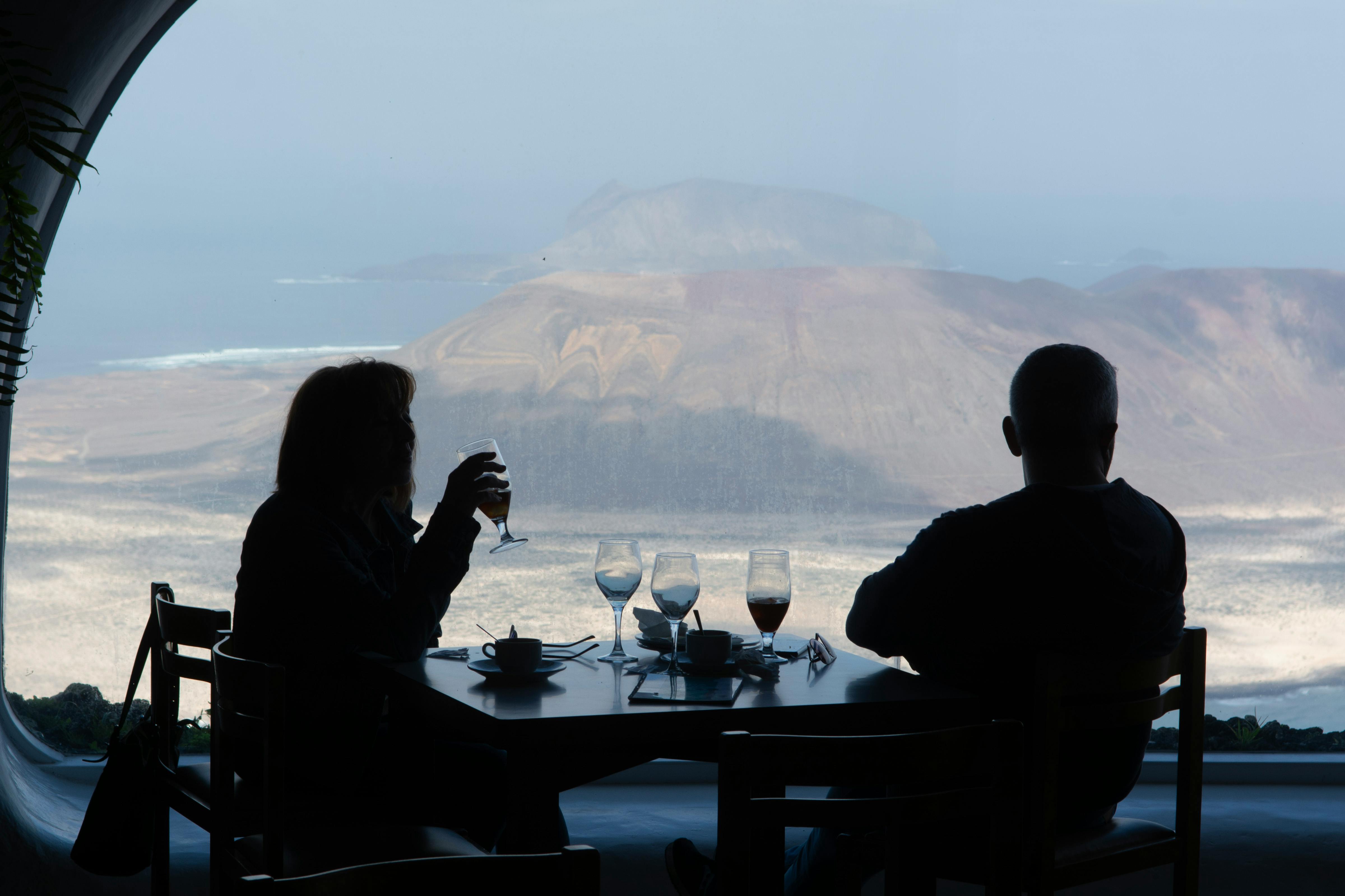 two people sitting at a table in front of a window overlooking the ocean