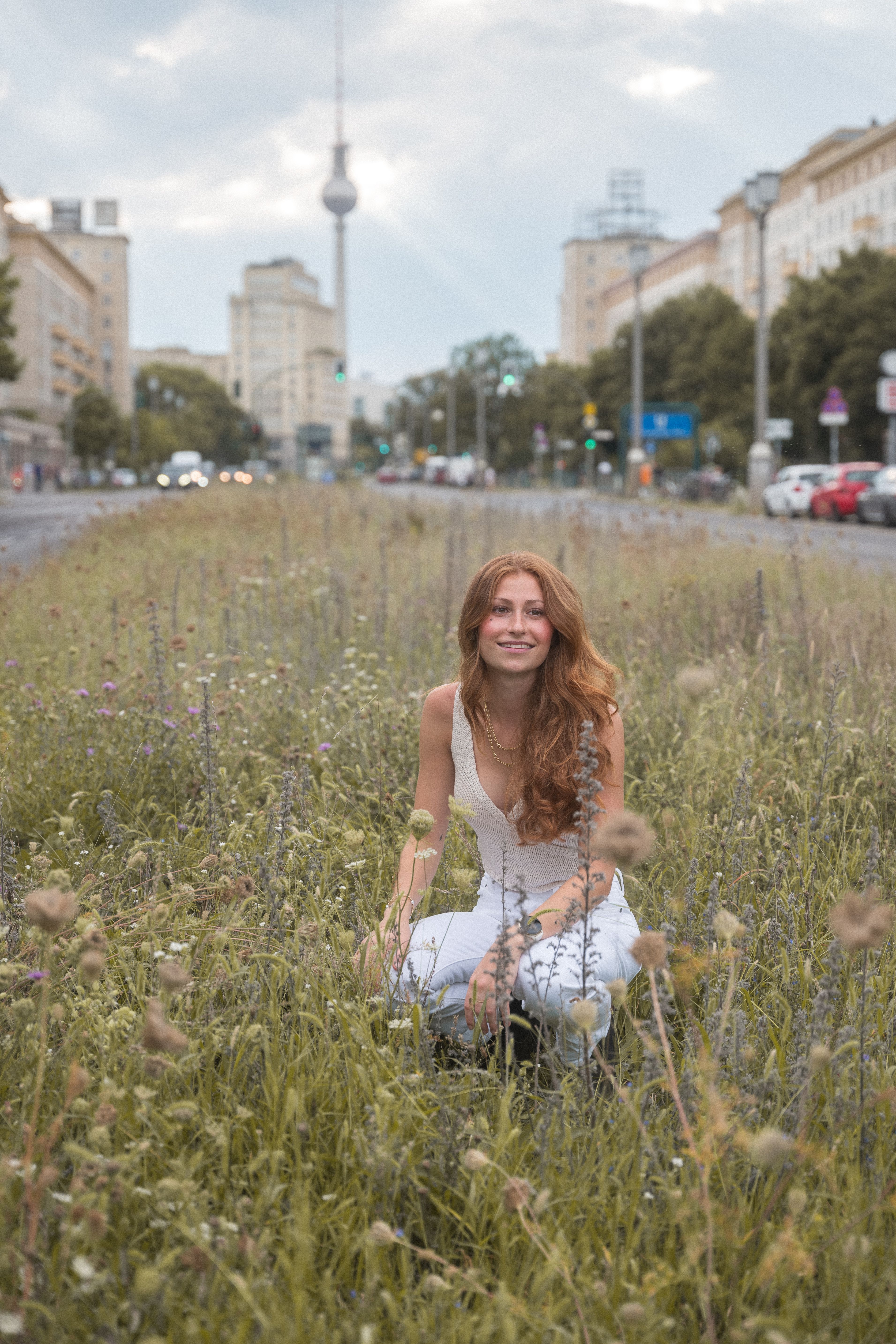 Woman enjoying a summer day in a Berlin park with a view of the TV Tower in the background.