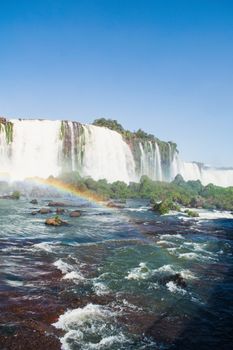 Breathtaking view of Iguazu Falls in Foz do Iguaçu, Brasil, with a vivid rainbow and lush greenery.