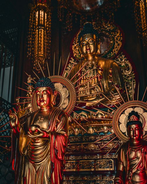 Free Intricate golden Buddha statues with sunburst halos in a richly decorated Buddhist temple interior in Hong Kong. Stock Photo