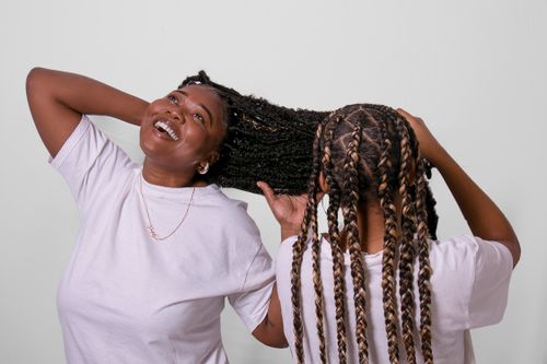 Free Two women with braided hairstyles enjoying a fun, casual moment indoors. Stock Photo