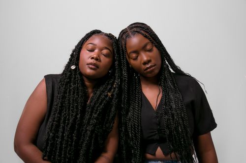 Free A stylish and serene portrait of two young women with braided hairstyles, expressing calm and unity. Stock Photo
