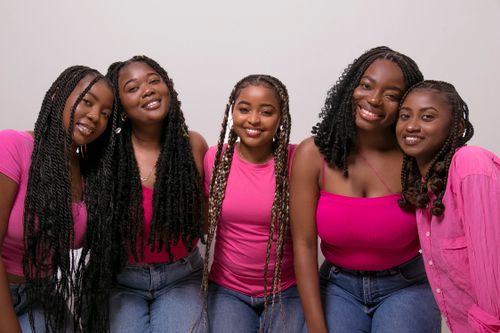 Free Five young women in pink tops smiling and embracing, showcasing friendship and joy. Stock Photo