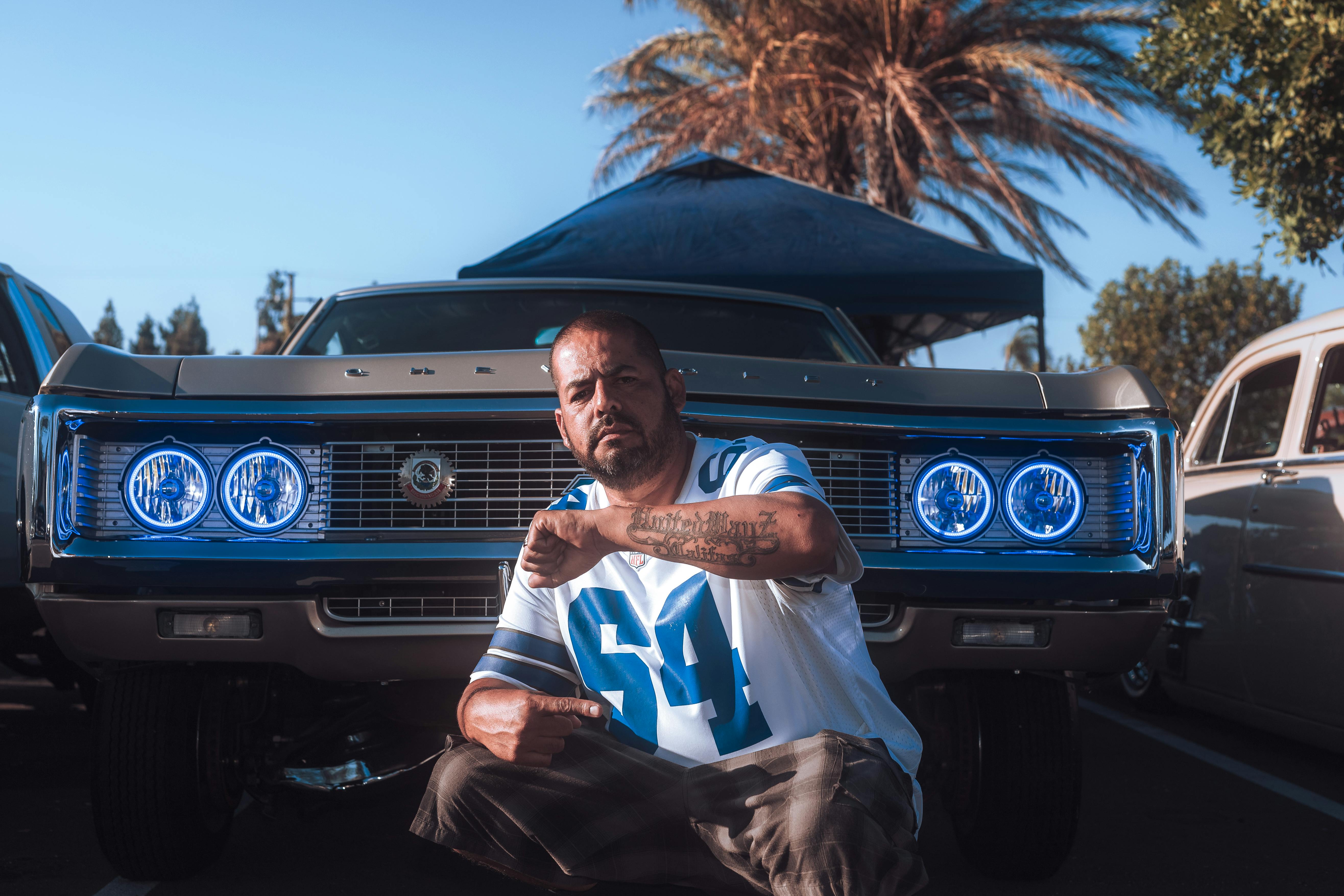 a man kneeling down in front of a car with blue lights