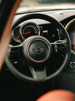 Interior view of a car showing a steering wheel and dashboard with dials.