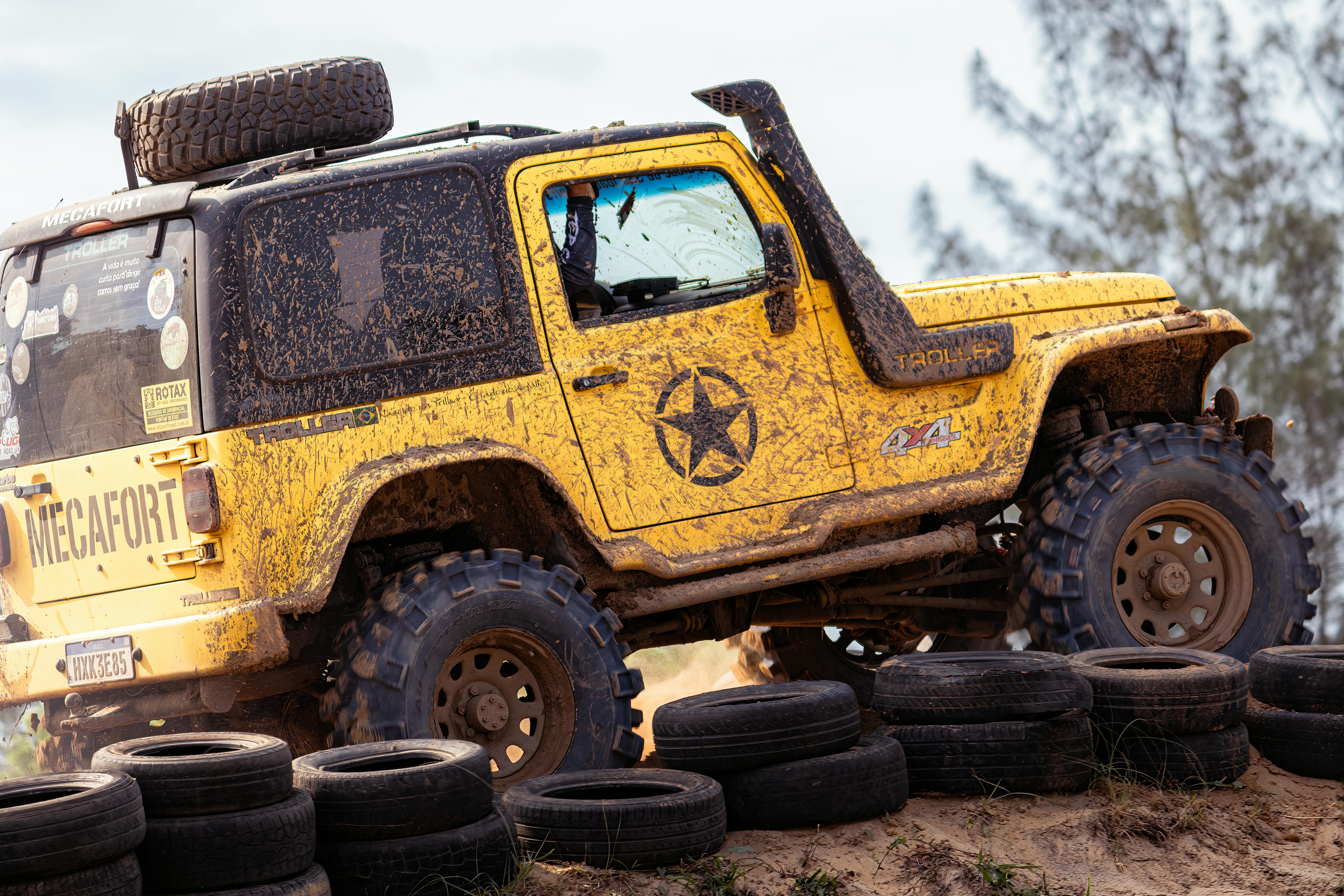 Yellow Jeep navigating muddy terrain on an off-road adventure, showcasing rugged vehicle capabilities.