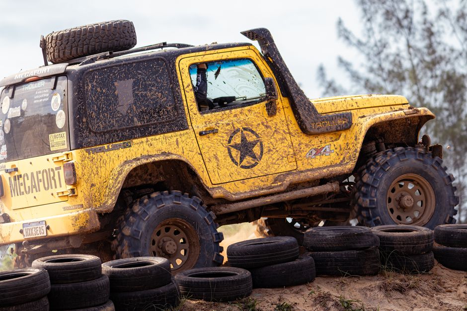 Yellow Jeep navigating muddy terrain on an off-road adventure, showcasing rugged vehicle capabilities.