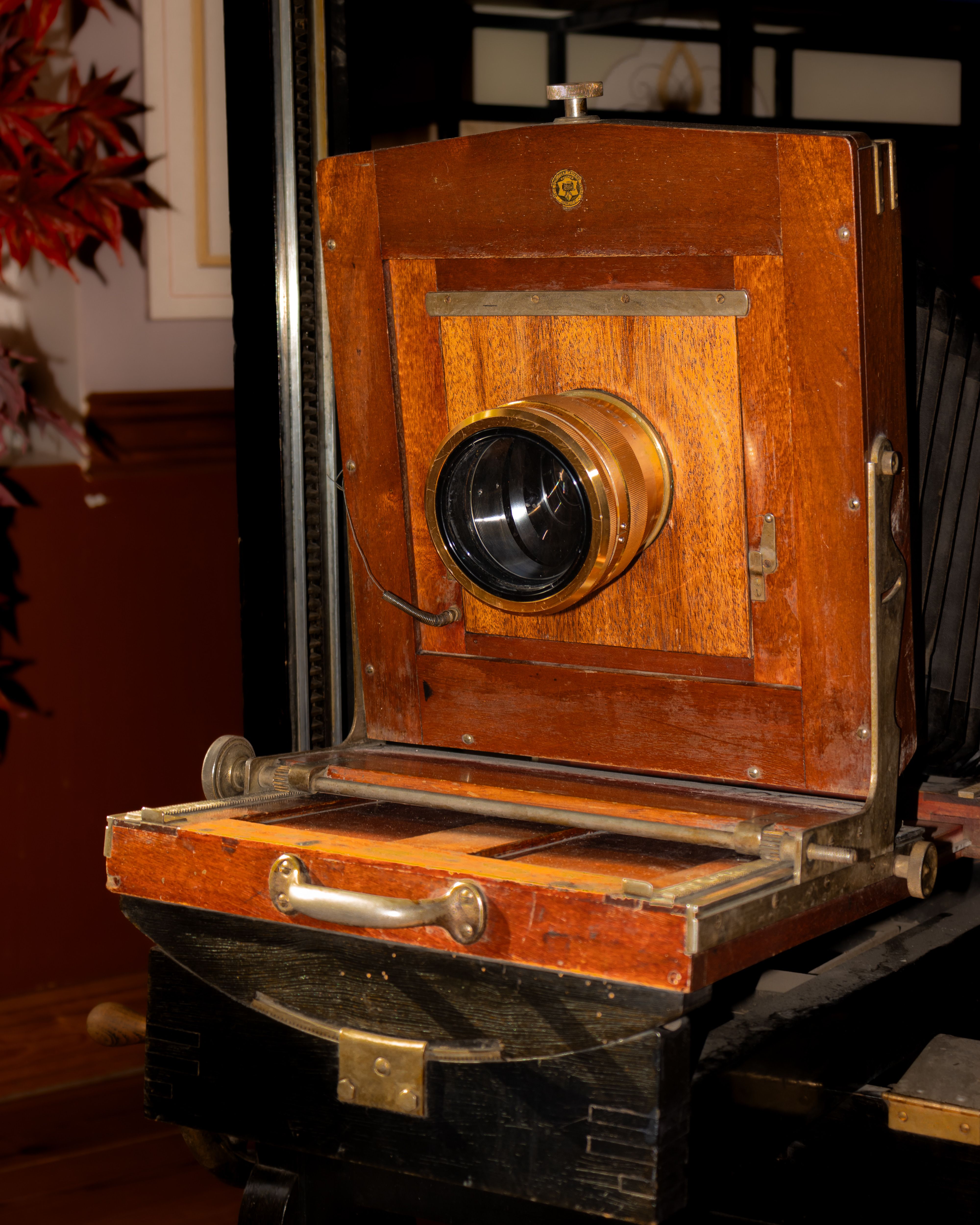 Close-up of a vintage wooden camera featuring a brass lens, evoking nostalgia.