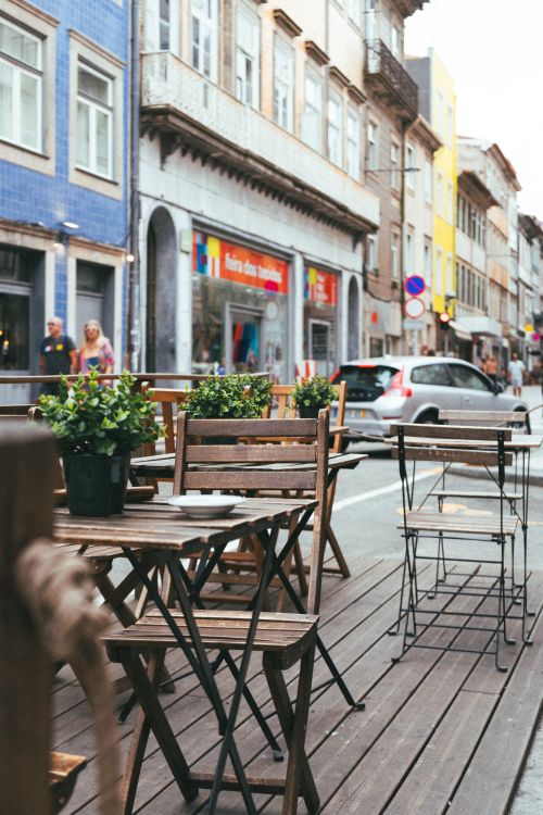 Free Outdoor cafe in Porto with wooden tables and chairs on a lively street. Perfect for relaxation. Stock Photo