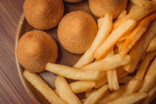 Free Close-up of golden croquettes and crispy fries on a wooden plate, perfect for a delicious snack. Stock Photo