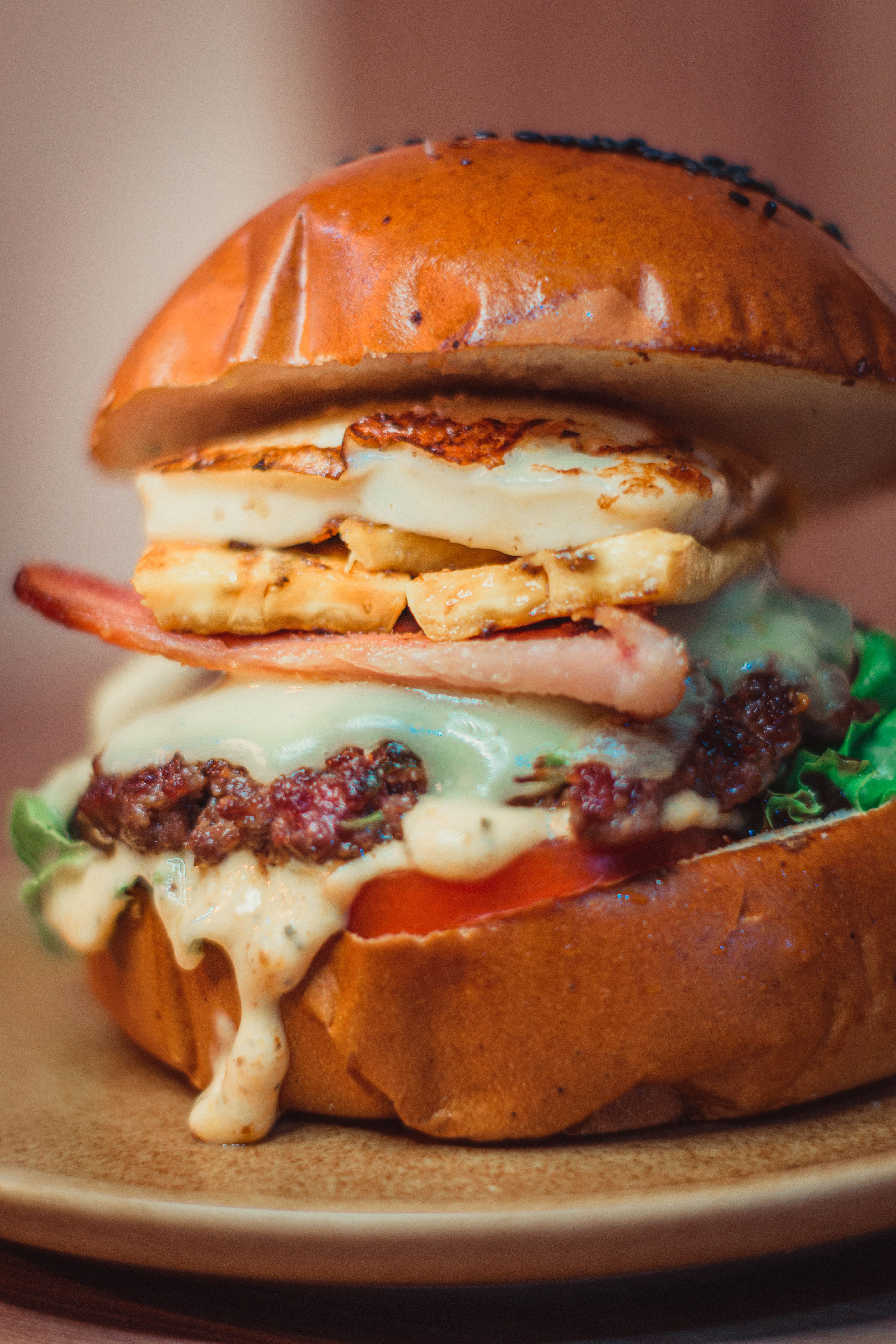 Delicious gourmet burger featuring cheese, grilled chicken, bacon, and fresh toppings on a sesame bun.