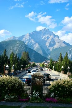 Capture of a bustling bridge with stunning mountain backdrop under a clear blue sky.