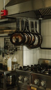An industrial kitchen setup featuring hanging pans and a modern stove in Ankara, Türkiye.