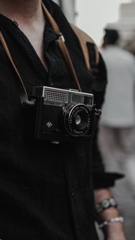 Close-up of a vintage camera hanging from a person's neck, creating a retro and stylish vibe.