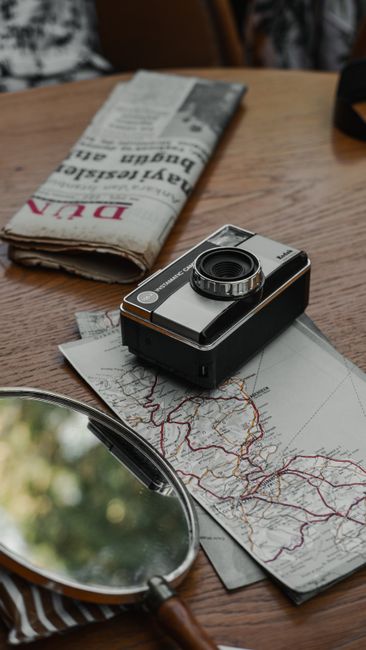 Retro camera and travel essentials on a wooden table capture a nostalgic travel vibe.