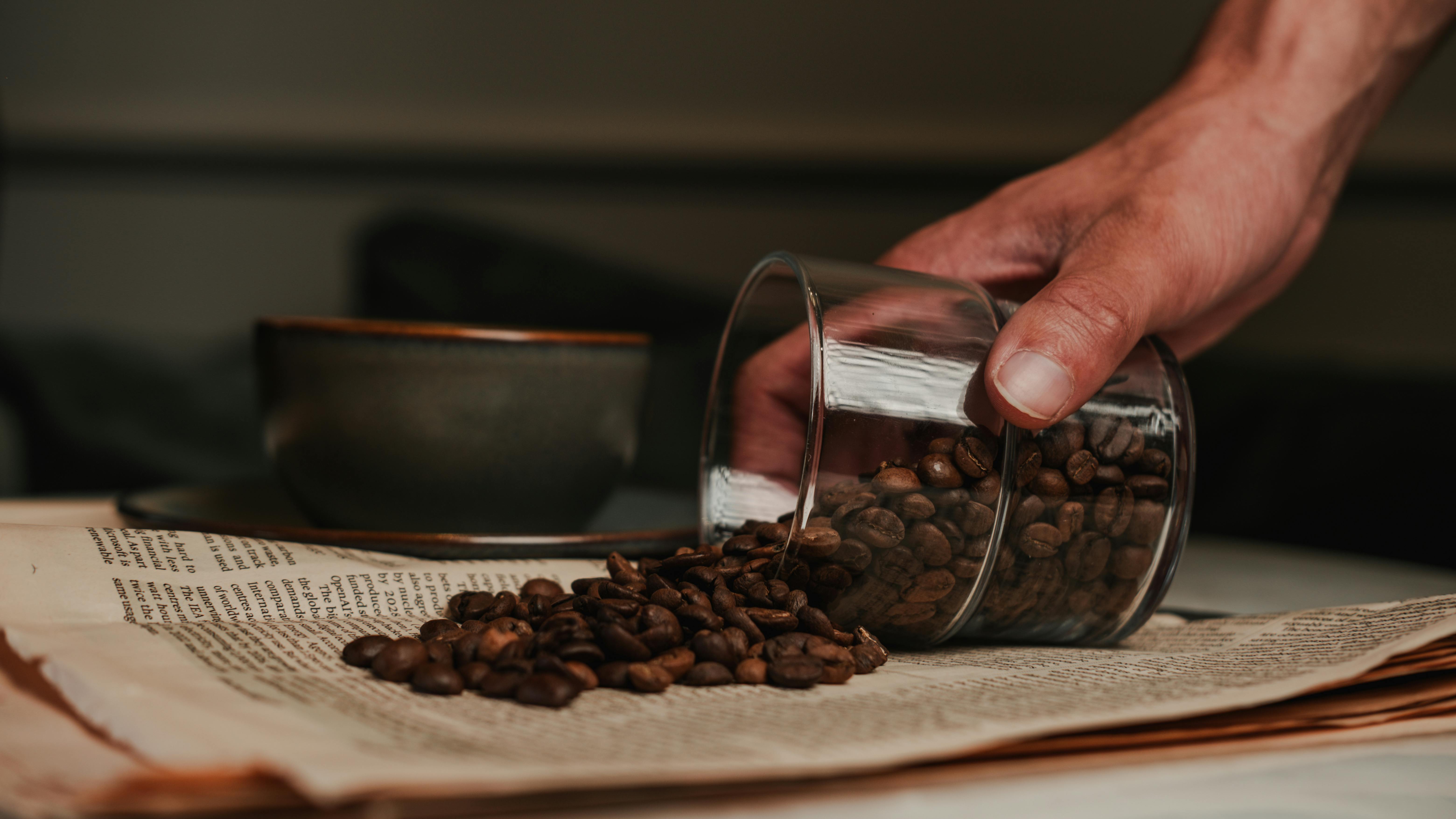 a person is pouring coffee beans into a cup on a table