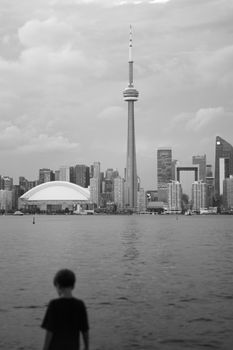 A child gazes at Toronto's skyline featuring the iconic CN Tower and cityscape.