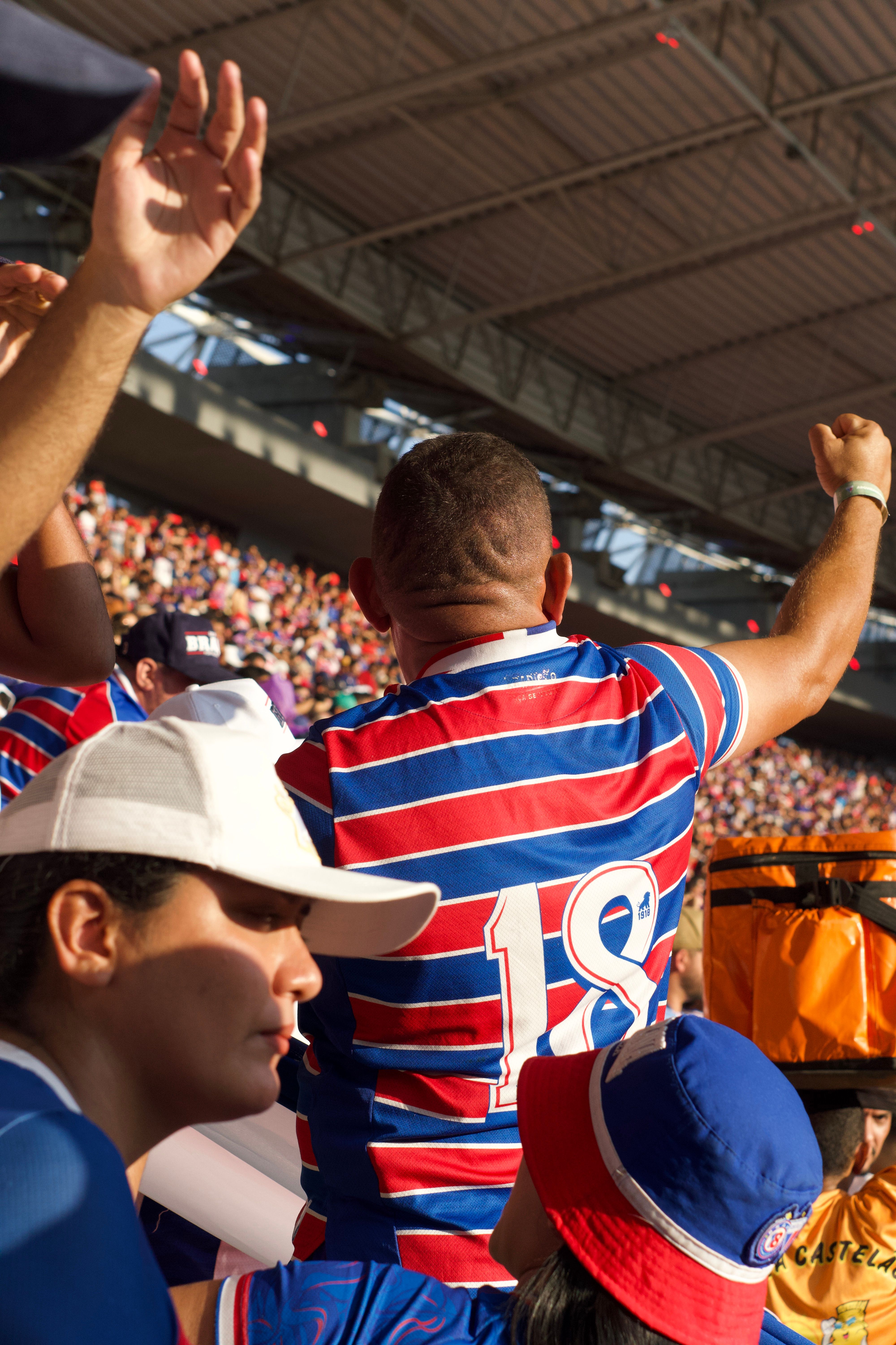 Enthusiastic sports fans cheer during a game at a vibrant outdoor stadium.