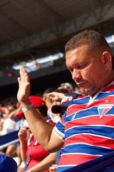 Excited football fan wearing striped jersey cheering at a soccer stadium during a live match.