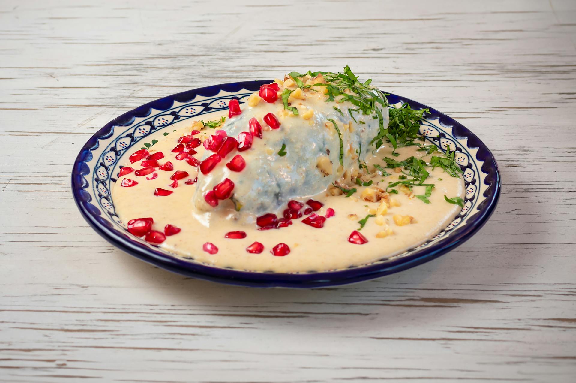 Delicious Chiles en Nogada, a classic Mexican dish, garnished with pomegranate seeds on a Talavera plate.