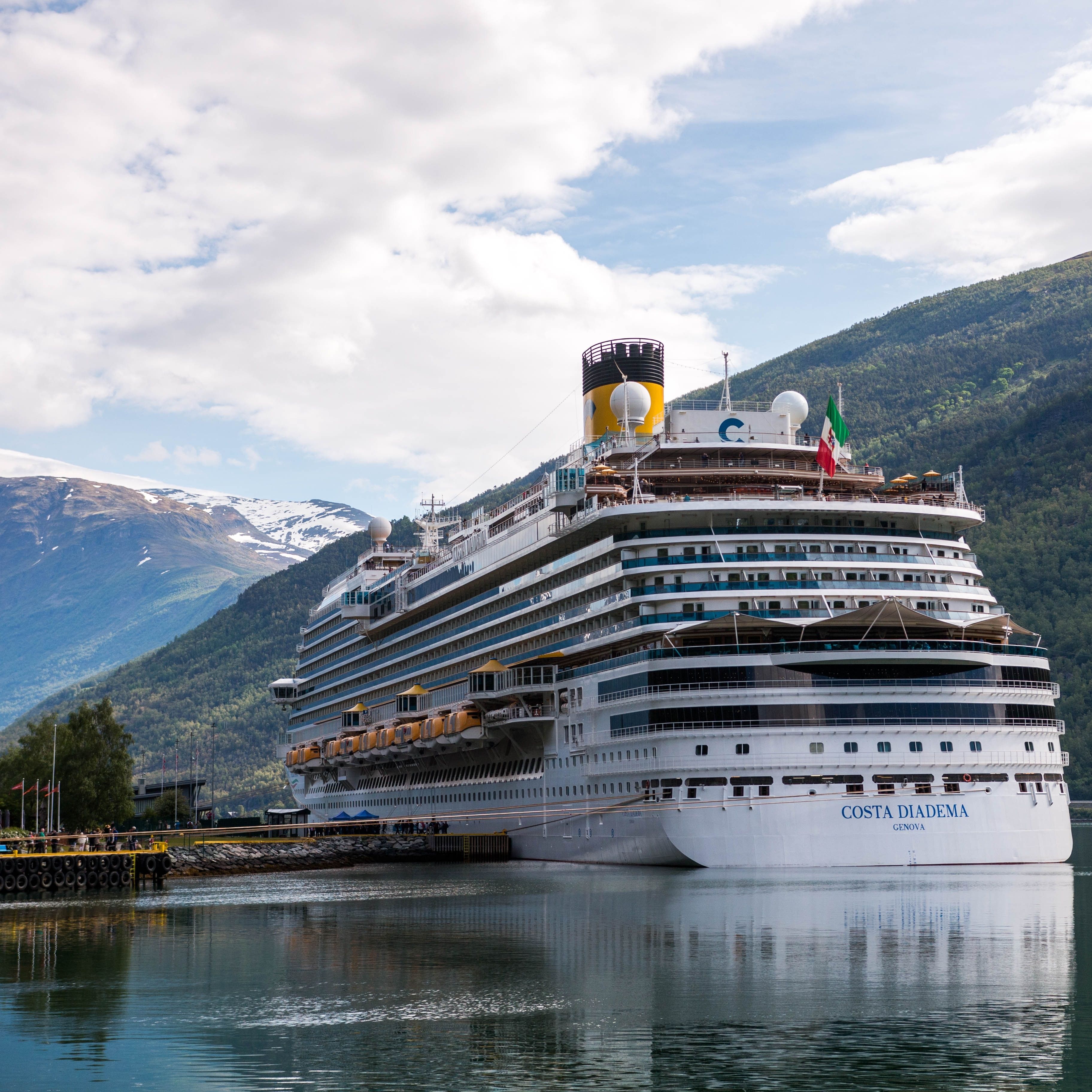 The Costa Diadema cruise ship moored in a picturesque harbor surrounded by mountains.