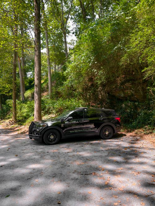 Free Police vehicle parked in a lush forest area on a sunny day. Stock Photo