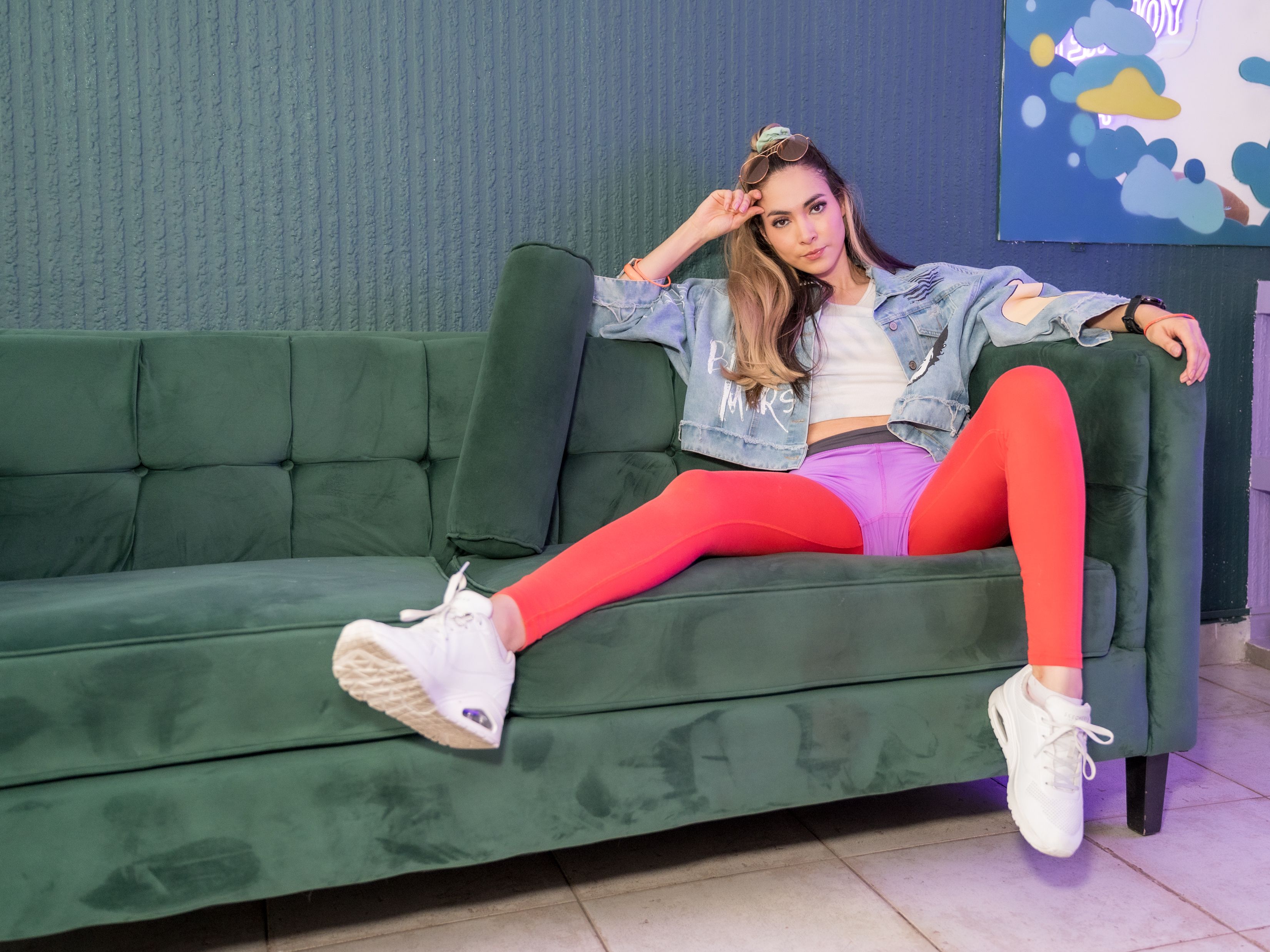 Fashionable woman in trendy outfit reclining on a green sofa indoors, Ciudad de México.